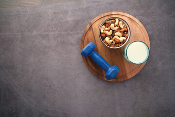 top view of glass of milk , dumbbell and mixed nuts in jar on black background