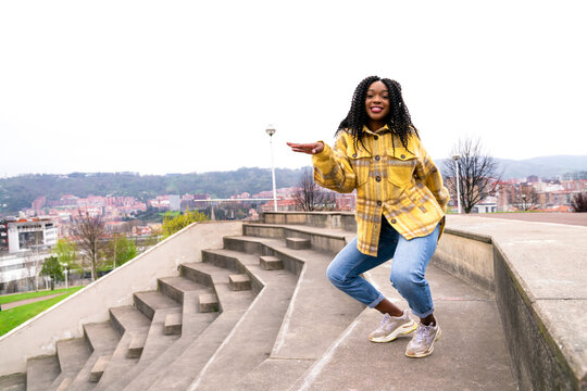 Energetic black woman dancing on concrete border