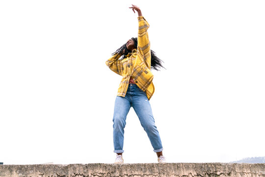 Energetic black woman dancing on concrete border
