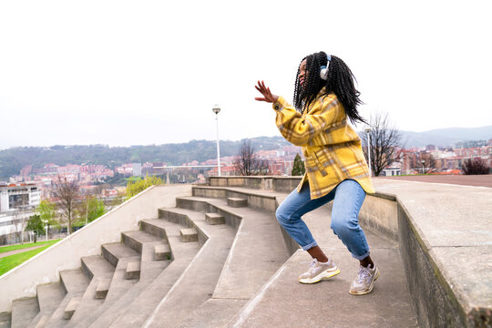 Energetic black woman dancing on concrete border