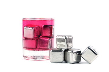 stainless steel ice cubes are on the wet white table with a glass of strawberry soda juice on background of white wall