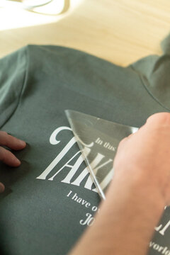 Crop unrecognizable person transferring letters on hoodie