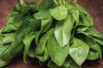 bunch of fresh spinach lies on a wooden table