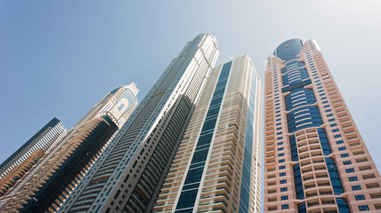 Fototapeta na wymiar Modern skyscrapers in the city under the blue sky on a clear day. Dubai Marina district. Architectural, construction or travel concept. Fastly developing city in Middle East. High quality photo