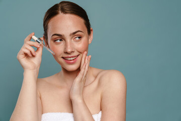 Smiling young woman applying facial oil serum drops