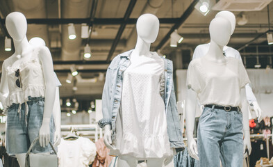 Mannequins in denim and white clothes in clothing store in shopping mall