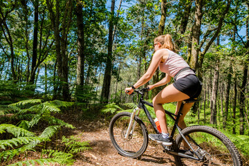 pretty young athletic woman mountain biking in nature