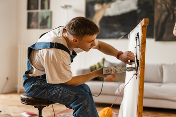 Young white man working on craft rug with sewing machine