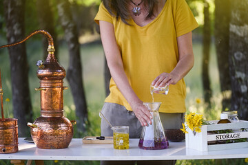 A woman's hands making essential oils at a work table in the field.