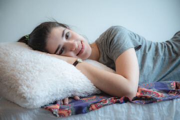 a young caucasian lady enjoy the moment on the bed, relaxing and fully rested smiling girl, sunrise sunshine wake up on the morning.