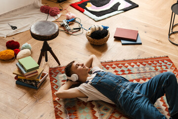 Young white man in headphones resting while working on craft rug