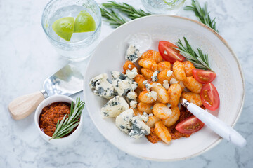 Plate of potato gnocchi with sun dried tomato pesto and gorgonzola cheese, studio shot on a...