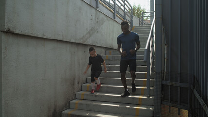 Diverse father and son running on concrete staircase together