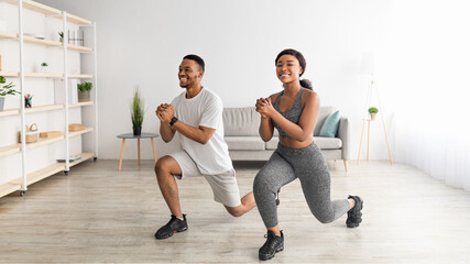 Obraz premium Home fitness. Full length of motivated black couple doing lunges in living room, banner design