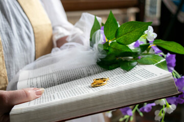 Wedding gold rings on bible with flowers and part of vicar in background