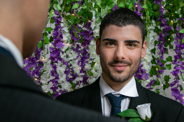 Gay men wedding ceremony with one groom looking at camera