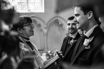 Gay men exchanging wedding rings in front of vicar in church