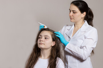 A dermatologist or trichologist applies a dandruff or lice weed to the patient's hair. Treating...