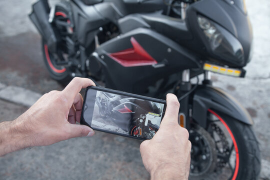 Man taking photo of a motorcycle on his phone.