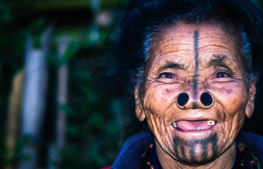 apatani tribal women closeup facial expression with her traditional nose lobes and blurred background