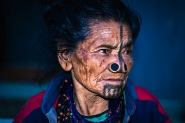 apatani tribal women facial expression with her traditional nose lobes and blurred background