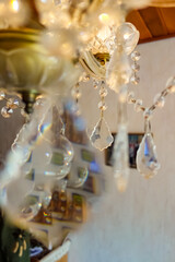 Kristallleuchter mit reflektierenden Glassteinen. Omas vintage Lampe an der Decke mit interessanten Lichtreflexionen. Kronleuchter mit tropfenförmigen Ornamenten.