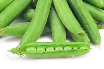 A pile of green pea pods. In the foreground lies one half-open pod