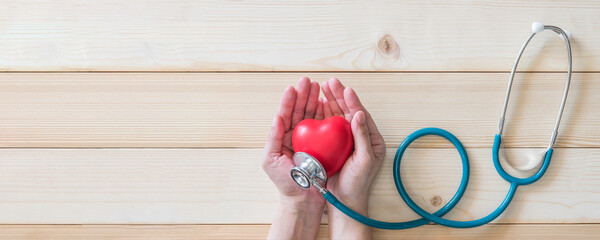 World heart health day concept with red heart and medical doctor stethoscope on aged woman hand for...