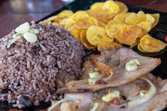 Cuban traditional cuisine, pork steak, banana fries, and congri rice