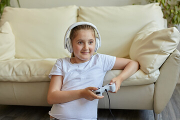 Pretty little girl in headphones are playing game console