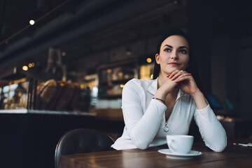 Pensive woman with cup of hot drink in cafe