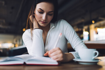 Young woman writing in notepad in cafe