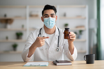 Doctor in face mask working at hospital, pointing at medicine