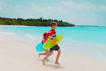 happy kids- boy and girl- go swim on beach