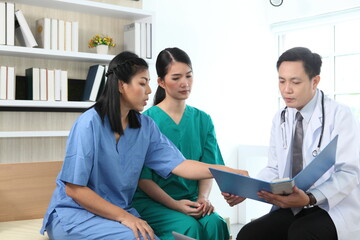Team of doctors and businesswoman having a meeting in medical office,Multiracial team of doctors discussing a patient standing grouped in the foyer looking at a tablet computer - Powered by Adobe