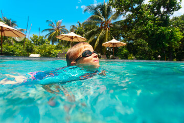 kid swimming at tropical beach resort, family vacation