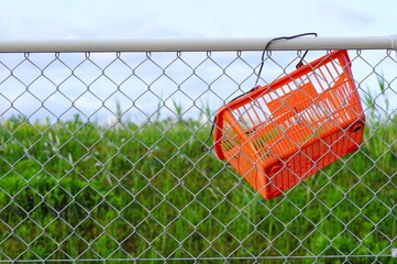捨てられて金網にかけられたスーパーのカゴ