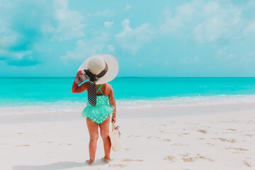 Fototapeta na wymiar rear view of little girl in big hat on summer beach