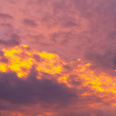 Evening sky in orange, red and yellow shades with cumulus clouds
