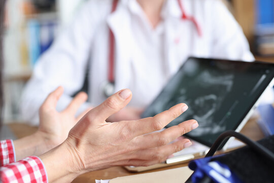Gynecologist demonstrates embryo ultrasound scan to woman on tablet screen