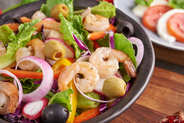 Healthy salad plate. Fresh seafood recipe. Grilled shrimps and fresh vegetable salad. Healthy food. Flat lay. Top view. Shrimp salad with tomato, olives and almond nuts. Mix vegetables.