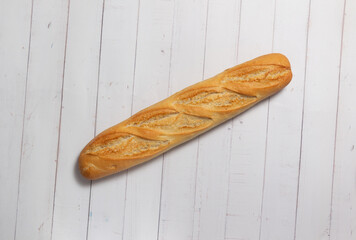 Bread bar perfectly baked on a white wooden background.