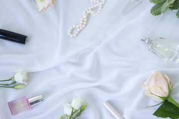 Perfume, flowers, jewelry, pearl, cosmetics on a white chiffon background. Feminine elegant fashion...