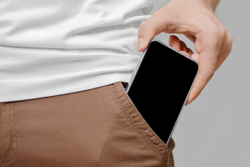 Close up of male hand taking out big mobile phone with empty black screen from front pocket of...
