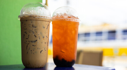 Coffee and iced tea paired up near green walls and street lighting.