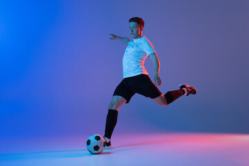 Young Caucasian man, male soccer football player training isolated on gradient blue pink background in neon light © master1305