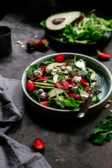 Salad with strawberries, feta, avocado and arugula in a plate on the table. Vegetarian salad
