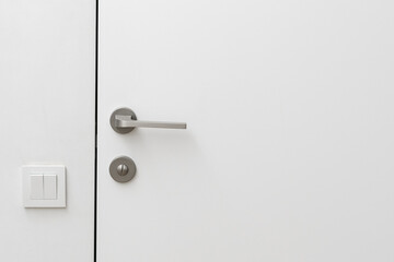Closed door and light switch on white wall