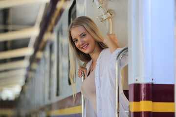 young woman waiting in vintage train, relaxed and carefree at the station platform in Bangkok, Thailand before catching a train. Travel photography. Lifestyle.