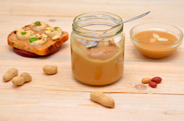 jar of peanut butter and peanuts sprinkled on the table